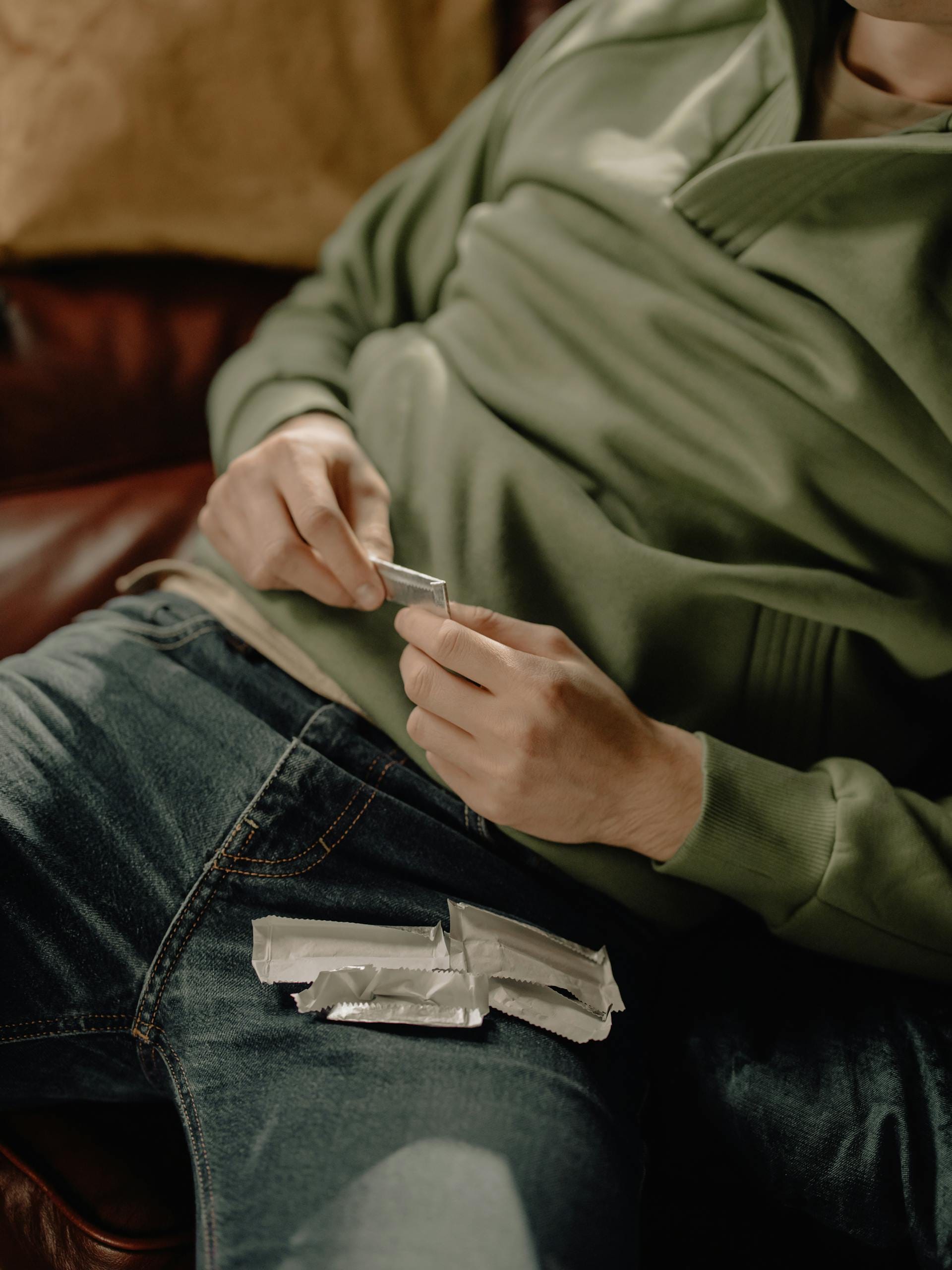 A person relaxing indoors, holding chewing gum, evoking a sense of tranquility at home.