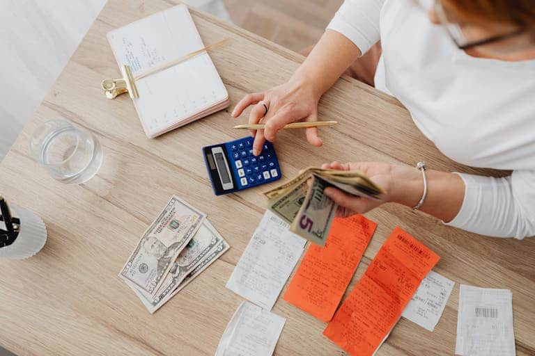 Person calculating cost of smoking per year Australia with calculator and money on table