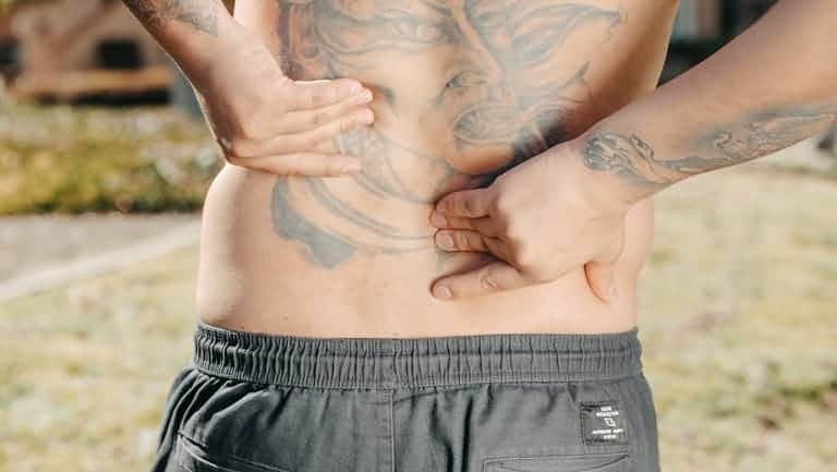 Smoking and Back Pain: The Surprising 79% Higher Risk Most Australian Smokers Don't Know About 7 A person holding their lower back in pain representing the surprising link between smoking and back pain and the 79% higher chronic pain risk smokers face