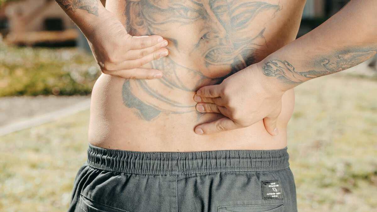 Smoking and Back Pain: The Surprising 79% Higher Risk Most Australian Smokers Don't Know About 1 A person holding their lower back in pain representing the surprising link between smoking and back pain and the 79% higher chronic pain risk smokers face